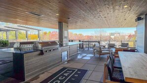 Un espacio al aire libre techado con una estación de parrillada, asientos y vistas de la ciudad.