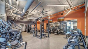 Un gimnasio con diverso equipo de ejercicio, incluyendo cintas de correr, máquinas de pesas y mancuernas.