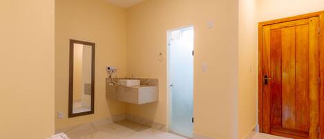 A bathroom with a marble floor, a sink with a mirror, and a wooden door.