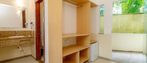 Un baño con encimera de granito, un espejo, un secador de pelo y una estantería de madera.