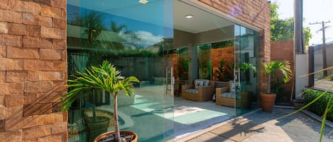 A modern building with a brick facade, large glass windows, and a patio area with potted plants.