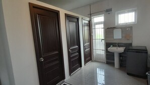 A narrow hallway with two wooden doors, a white sink, a mirror, and a window. - Cozy Appartment (Ebene City)