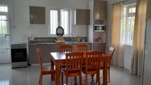 A modern kitchen with a dining area, featuring a built-in oven, microwave, and a sink. - Cozy Appartment (Ebene City)