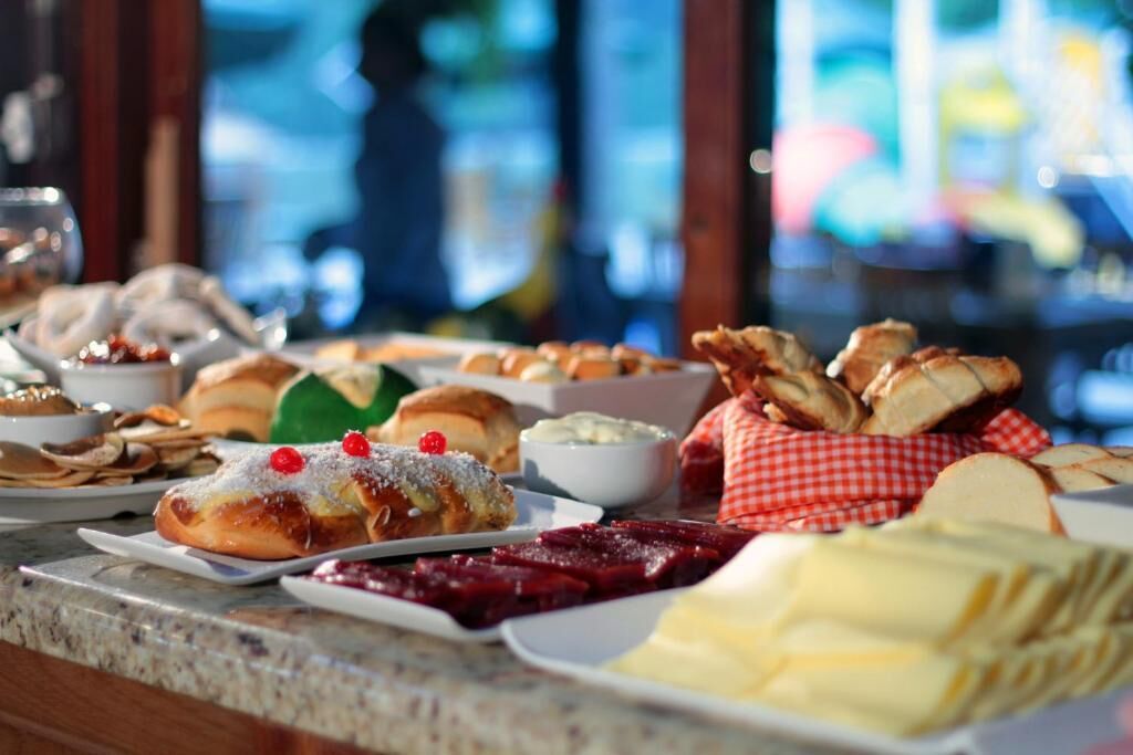 A buffet with various pastries and desserts, including cakes and bread, arranged on a counter.