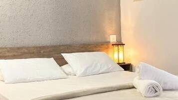 A hotel room with a bed, a nightstand, a lamp, and an air conditioning unit.