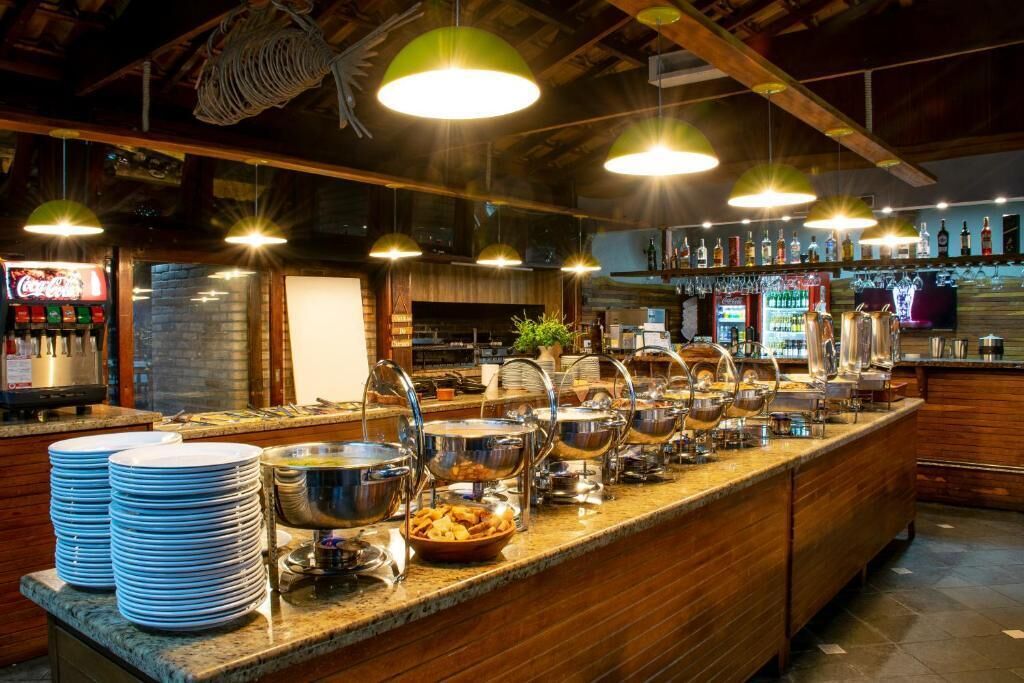 A buffet setup with multiple serving stations, a bar area with various liquor bottles, and a seating area with a television screen.