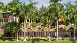 Un complex turístic amb diverses edificacions de tipus bungalot, una piscina i vegetació exuberanta.