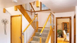 A staircase with wooden railings and carpeted steps leading to an upper floor.