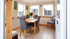 A dining area with a wooden table, six chairs, and a vase of flowers. - 3BR Cottage w/ Garden, Free Parking for 6 Guests (Ardross)