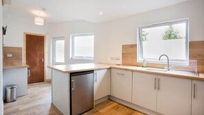 A modern kitchen with a dishwasher, a sink, and a window providing natural light. - 3BR Cottage w/ Garden, Free Parking for 6 Guests (Ardross)