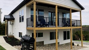 Een huis met twee verdiepingen, een balkon, een barbecue en uitzicht op het omliggende landschap.