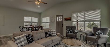 A living room with a sofa, armchairs, a coffee table, and a ceiling fan.