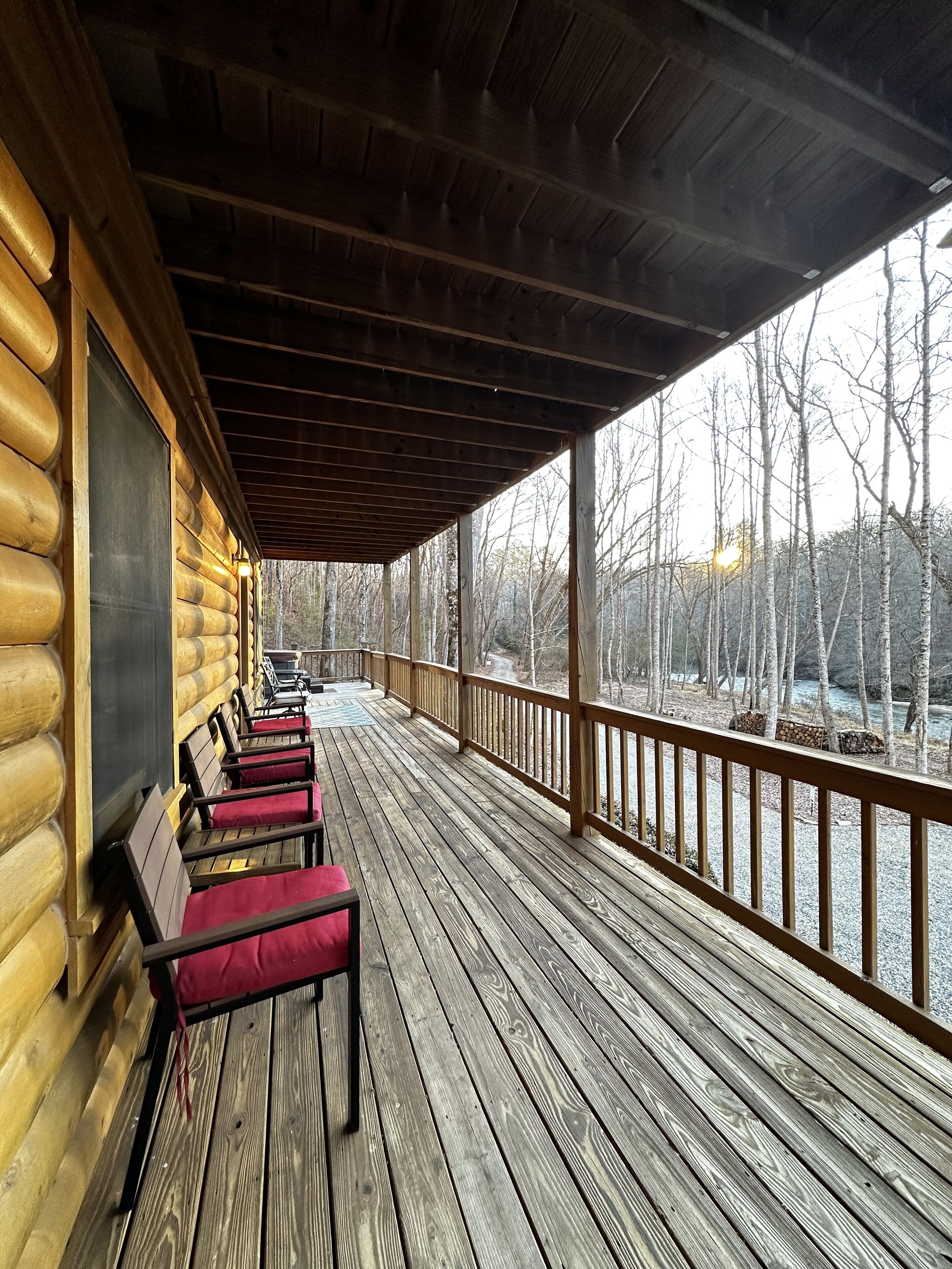 A wooden deck with benches and a view of a forest.