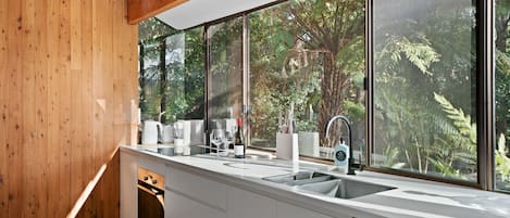 A modern kitchen with a large window, wooden walls, and a built-in dishwasher.