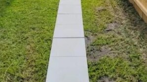 Ein Garten mit Holzzaun, Betonweg und Backsteinmauer.