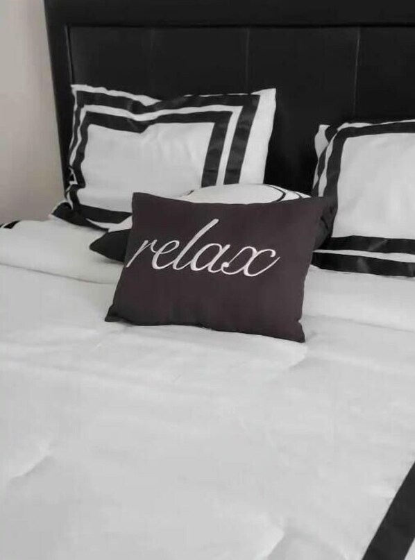 A bed with black and white striped pillows and a pillow with the word "relax" on it.
