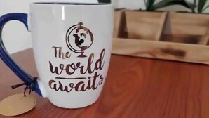 Una taza blanca con un globo y texto, sobre una superficie de madera.