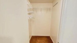 A narrow hallway with a wooden floor leading to a closet with a metal rack. - Private studio next to FT Stewart (Hinesville)