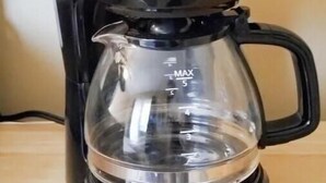 En kaffemaskine i sort farve med en klar glaskande og en sort bund.