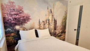 Ein Schlafzimmer mit einem großen Bett, einer weißen Wand und einem Wandbild von Burg und Kirschblüten.