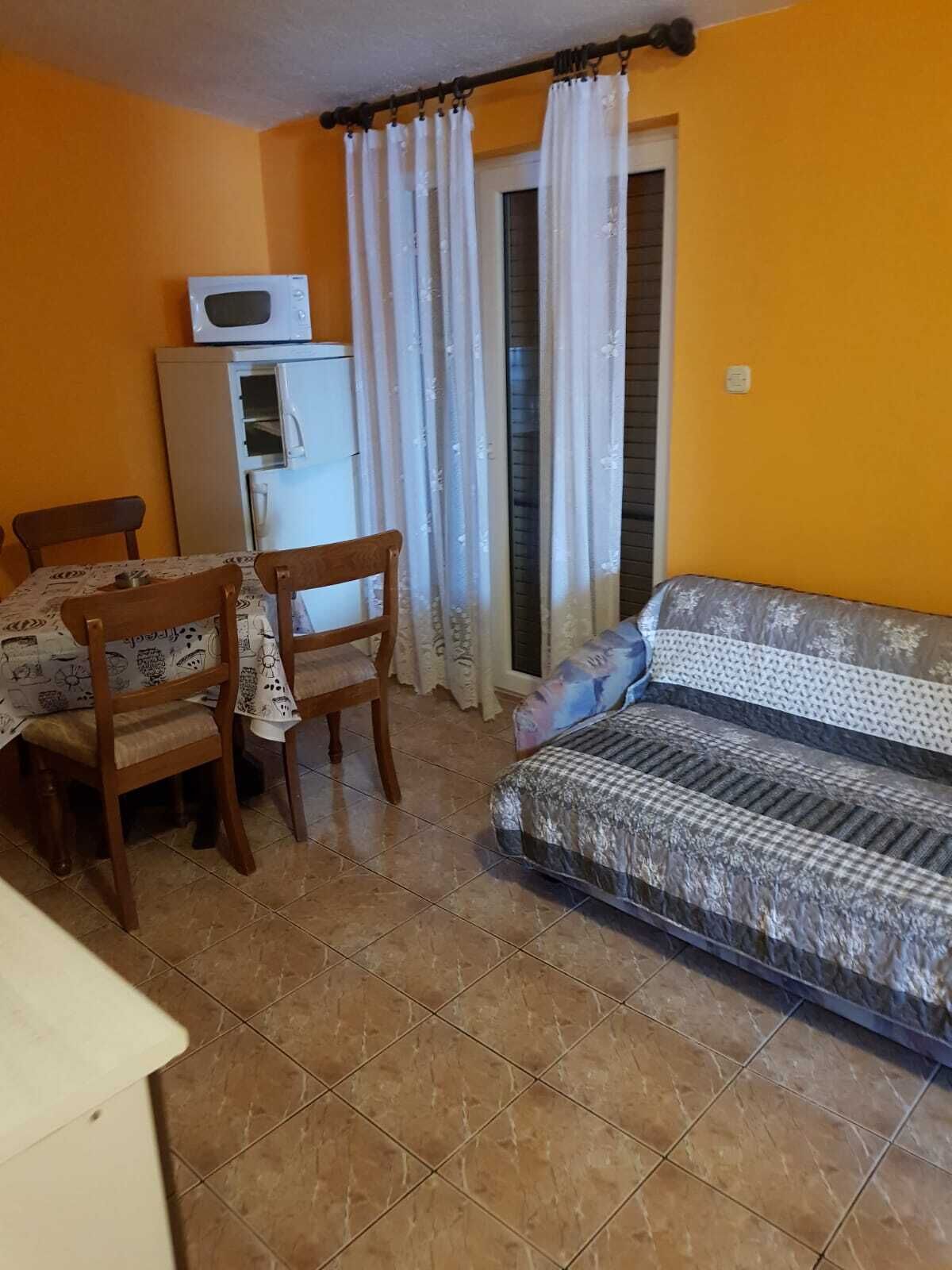 Un ambiente compatto con divano, tavolo da pranzo con sedie, frigorifero e forno a microonde.