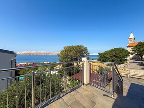 Ein Balkon mit Blick auf das Meer, eine Kirche und eine Steinmauer.