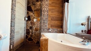 Un baño moderno con cabina de ducha de piedra, bañera independiente y retrete.