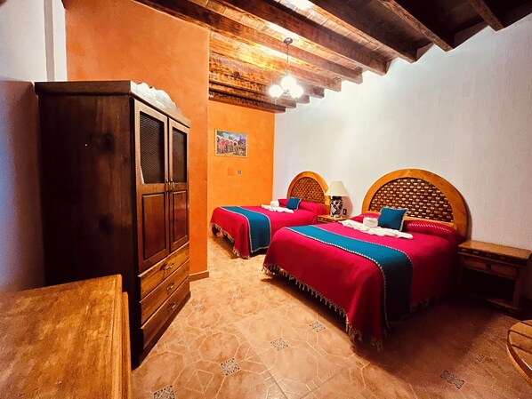 Una habitación con dos camas, un armario de madera y suelo de baldosas.