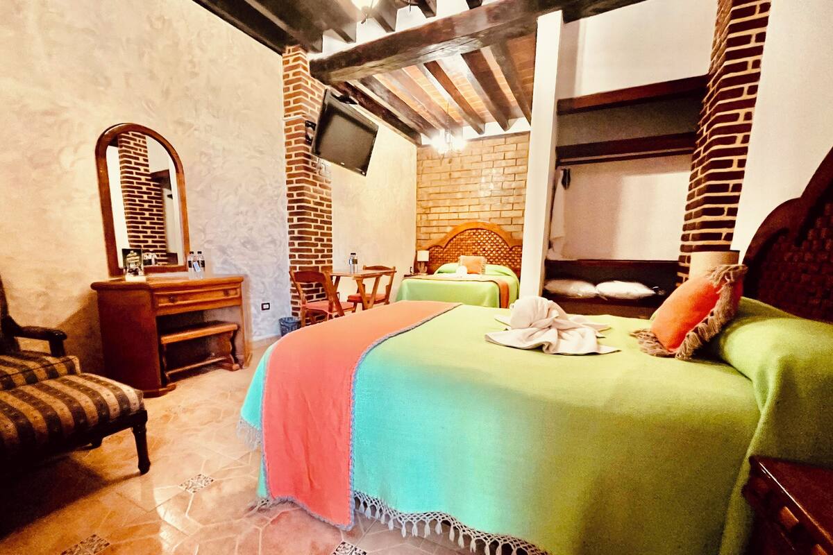 Ein Hotelzimmer mit einem Bett, einem Schreibtisch, einem Stuhl, einem Fernseher und einer Ziegelwand.