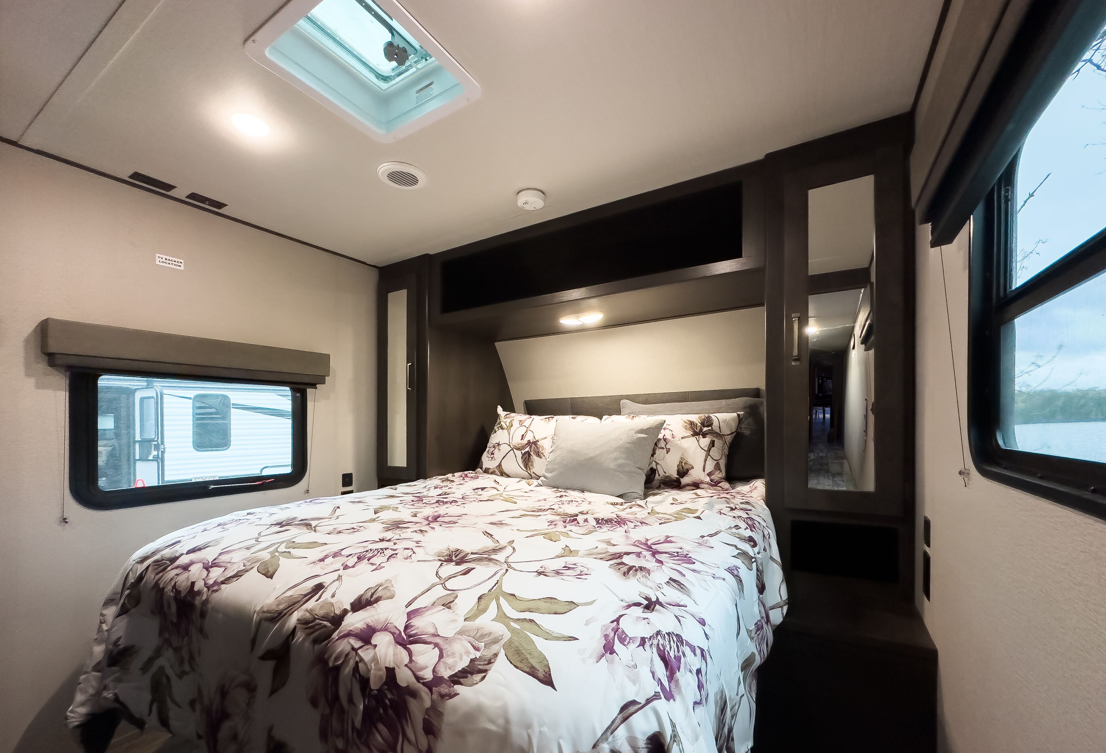 A bedroom with a bed, a skylight, a window, and a door to the outside.