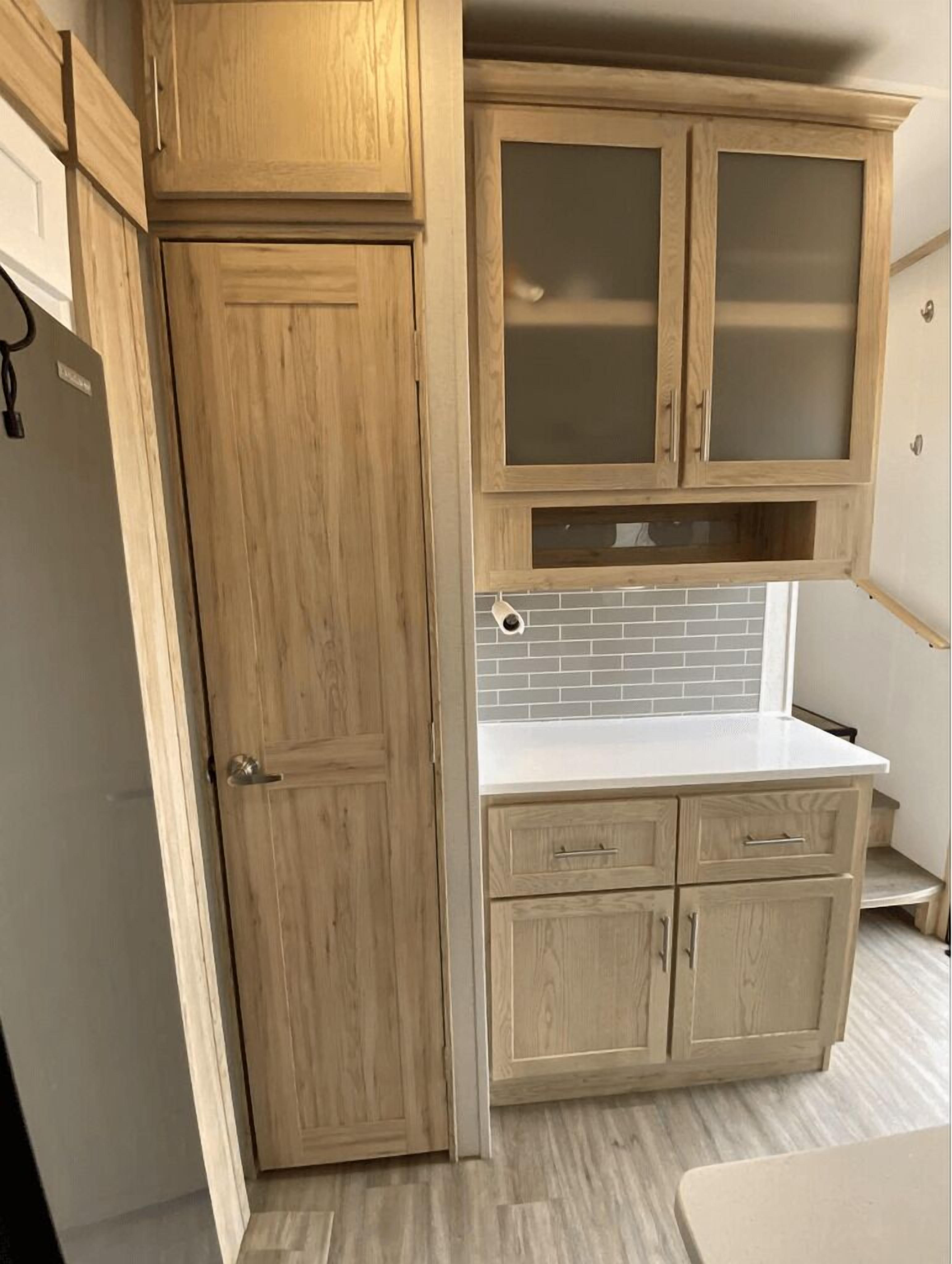 Una cocina con armarios de madera, encimera blanca y salpicadero de azulejos.
