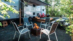 Un véhicule récréatif doté d’une terrasse couverte, de sièges extérieurs et d’un foyer.