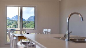 A modern kitchen with a large window offering a mountain view. - Ambience - Freycinet Holiday Houses (Coles Bay)