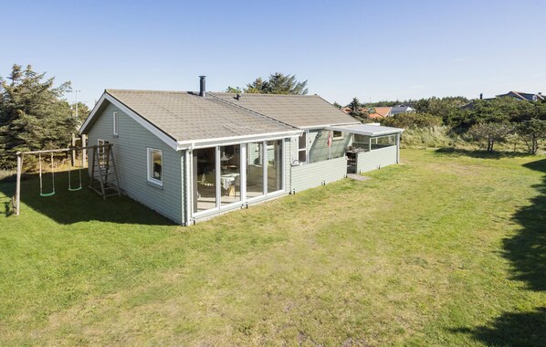 A two-story house with a covered patio and a swing set in the yard.