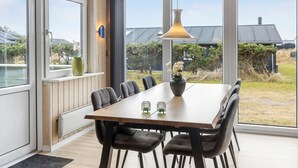 A dining area with a wooden table, six chairs, two vases with flowers, and a pendant light. - Lovely home in Thisted with kitchen (Thisted)