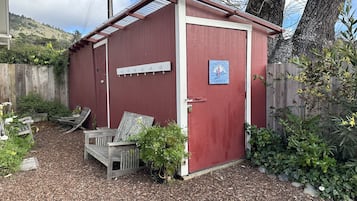 Situated in a serene garden, this charming shed offers a peaceful retreat with a bench and bird feeder nearby.