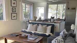 Una sala de estar moderna con un sofá, una mesa de centro y una zona de cocina con estufa y refrigerador.
