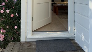 Una puerta blanca con el número 40, que da a una habitación con suelo de madera, una pequeña mesa y una silla.