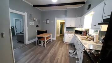 A modern kitchen with white cabinets, a wooden dining table, and a built-in stove.