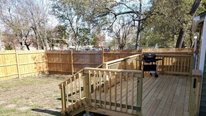 A backyard deck with a wooden railing and a barbecue grill. - Home Away From Home

 (Warrensburg)