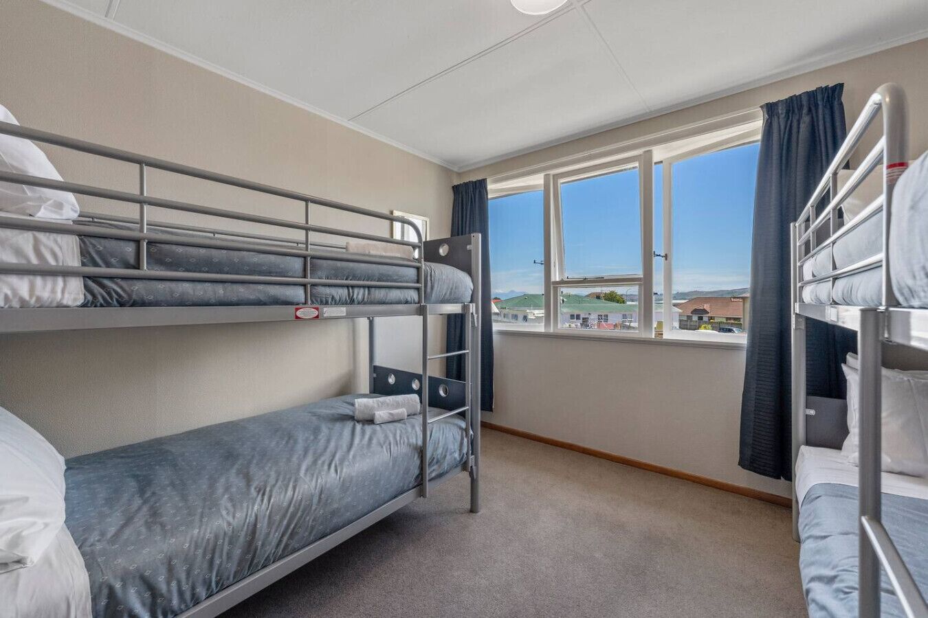 Un dormitorio con literas, una ventana con vistas y suelo cubierto de alfombra.