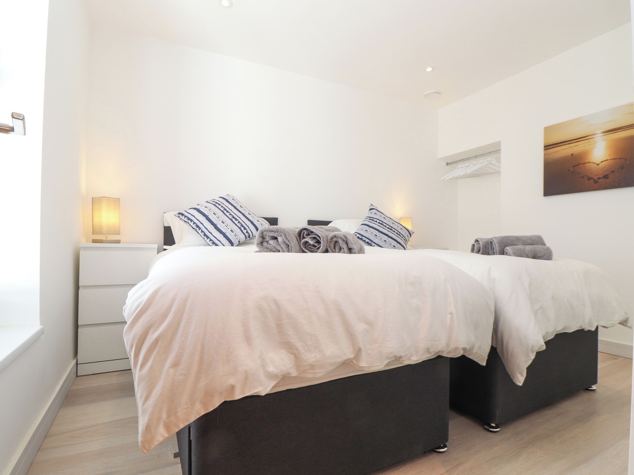 Une chambre moderne avec un grand lit, des lampes de chevet et un tableau au mur.
