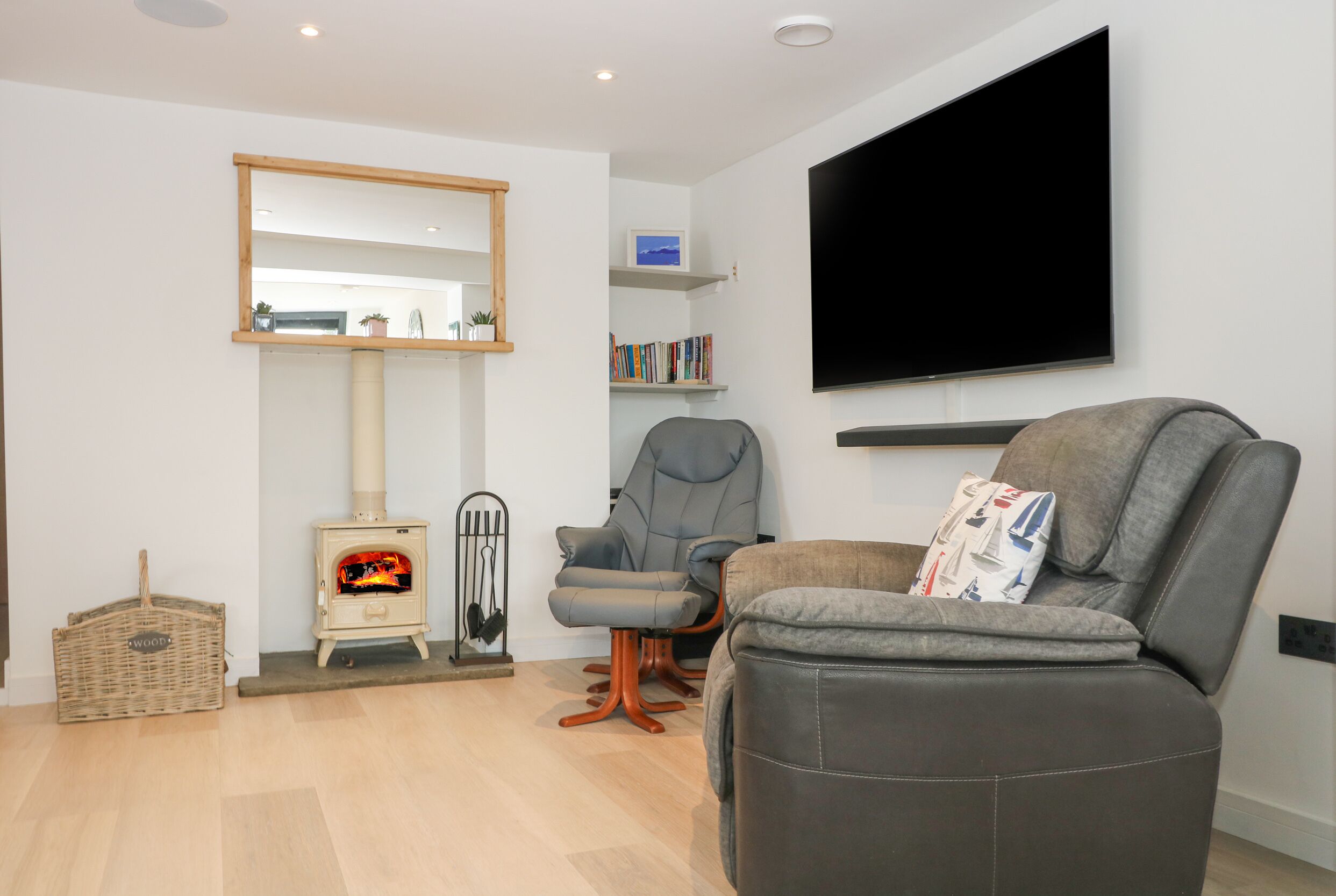 Ein modernes Wohnzimmer mit Kamin, gemütlicher Sitzecke, einem Wand-Fernseher und einem Bücherregal.