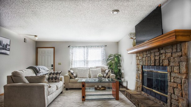 A living room with a sofa, a glass coffee table, a fireplace, and a stone wall.