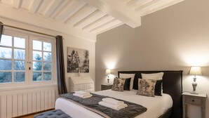 Una camera da letto con un letto grande, due comodini con lampade, una finestra con tende e un quadro appeso al muro.