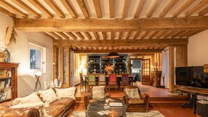 Un ampio soggiorno con soffitto in legno, divani in pelle, un tavolino da caffè e una zona pranzo con sedie colorate.
