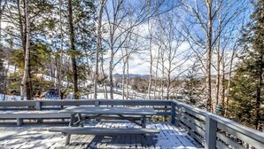 A wooden deck with benches, surrounded by trees and a snowy landscape. - Lift Haus - New Trailside 2br Condo at Attitash - Clean • Modern • Easy (Bartlett)