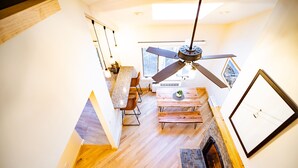 A modern kitchen with a wooden floor, a dining area with a bench, and a fireplace. - Lift Haus - New Trailside 2br Condo at Attitash - Clean • Modern • Easy (Bartlett)