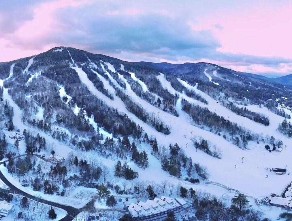 Une montagne enneigée, avec des pistes de ski et un petit bâtiment dont le toit est recouvert de neige.