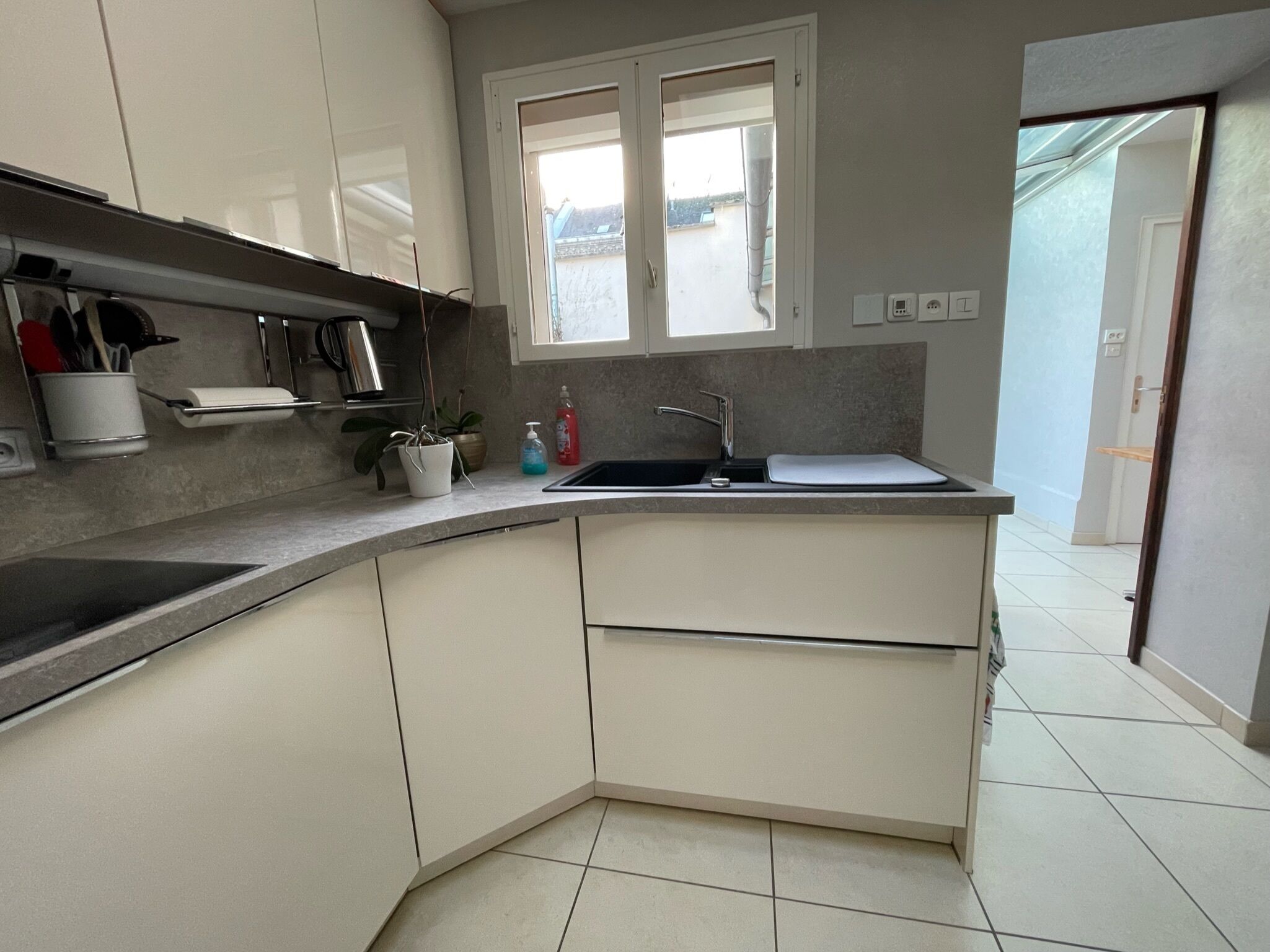 Una cocina moderna con armarios blancos, un lavamanos de acero inoxidable y una ventana sobre la encimera.